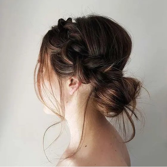 an elegant yet messy low bun with a side braided halo and some locks down for a cool look
