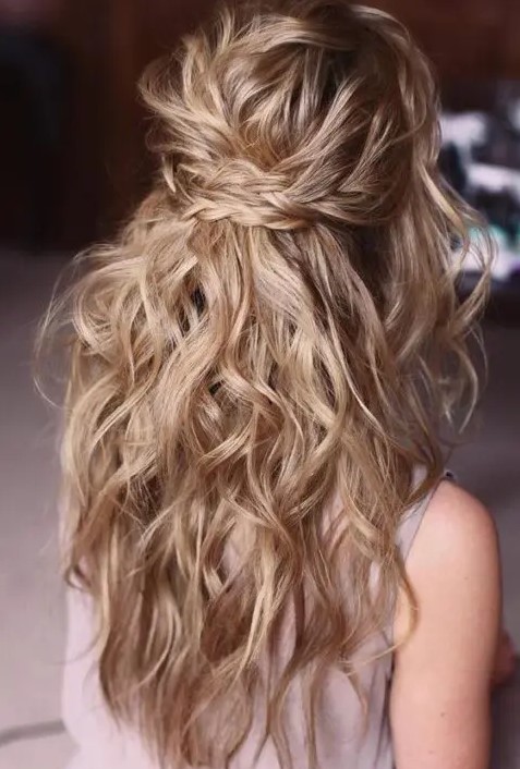 a messy and wavy half updo with two braids as a halo and waves down is a beautiful idea for a boho bride