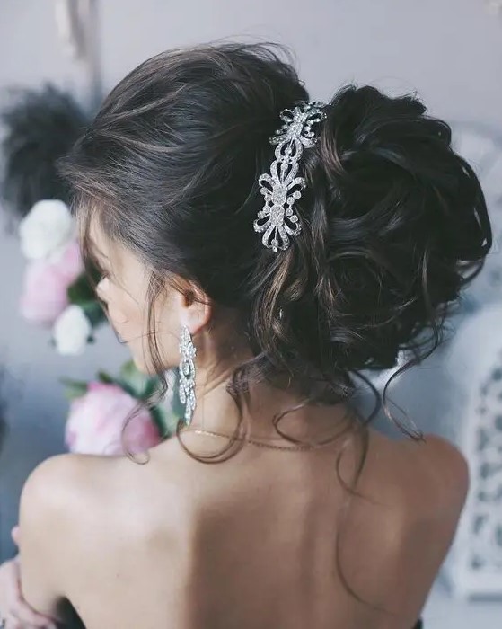 a beautiful and elegant updo with a volume on top and a large amount of curls, with some locks down and a large rhinestone headpiece