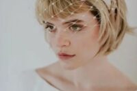 47 a short blonde bob with bangs, a knot headband and a birdcage veil for a retro touch to the look