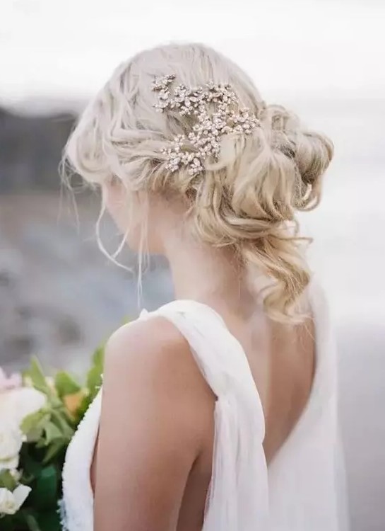 a wavy and messy updo with curls down and a sparkling rhinestone headpiece for a real Greek goddess look