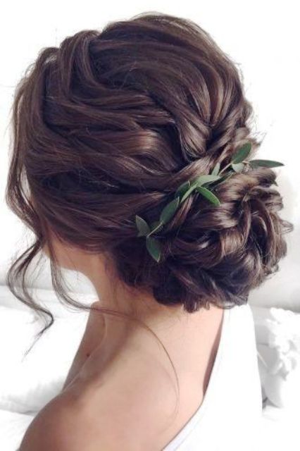 a wavy low bun with a wavy top and a wavy bun, with some locks down and a greenery touch is a chic and lovely idea