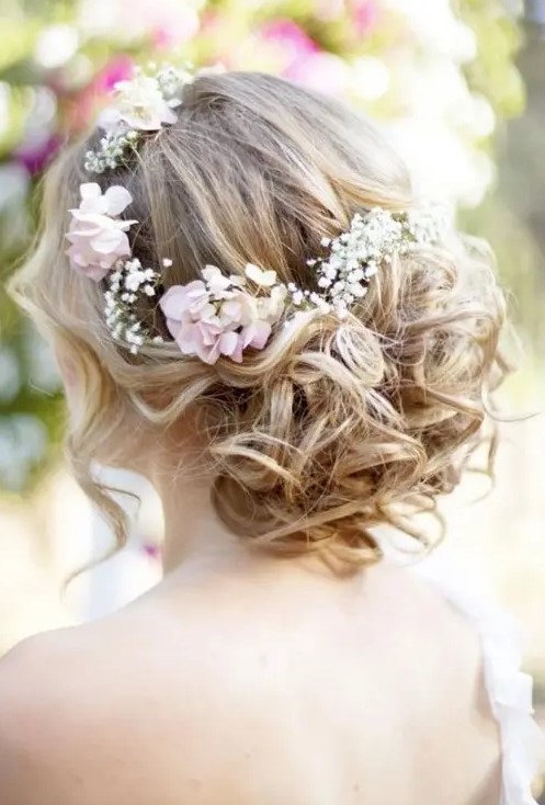 a wavy low updo with locks down and some fresh blooms tucked into the hair is a romantic idea for a boho chic bride