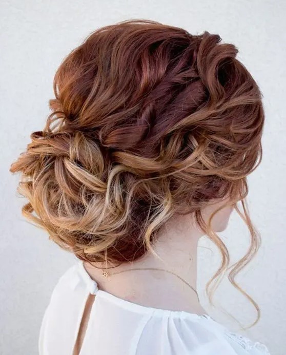 a wavy messy updo with locks to frame the face and a low bun plus an ombre effect is a chic and lovely idea for a wedding
