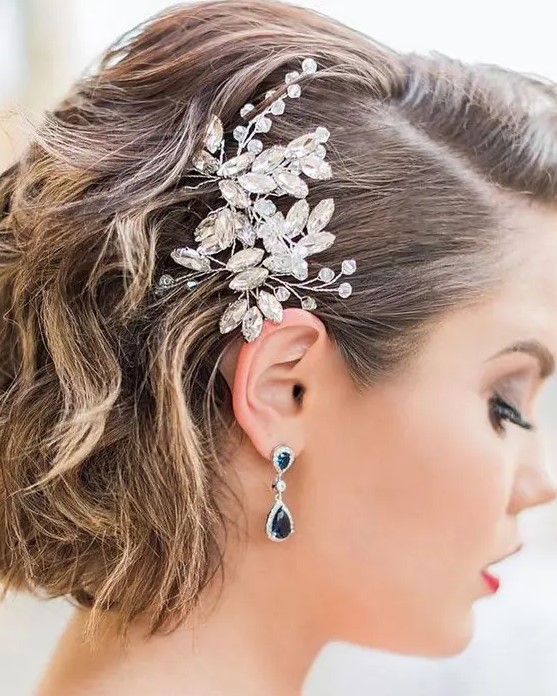 short curly wedding hair with side parting and a large and beautiful crystal hairpiece is a very refined and chic idea for a wedding