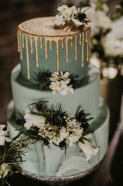 a sage green wedding cake with a marble tier, white blooms and thistles and a gold drip on top is a lovely and catchy idea
