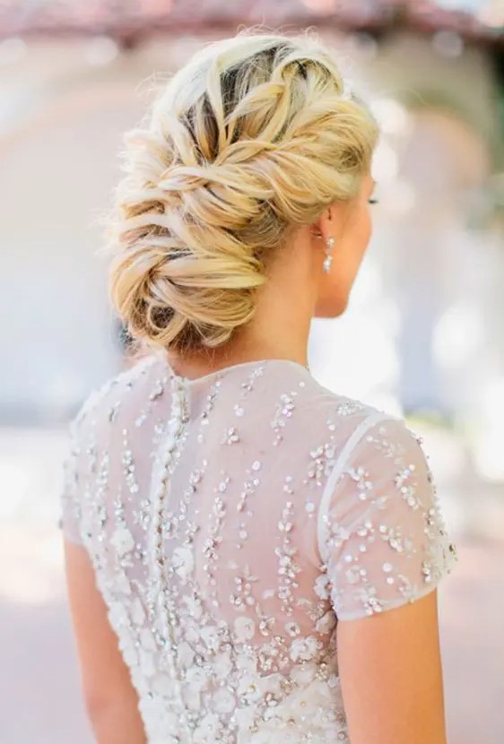 a low and loose twisted wedding updo with a volume on top is great for long hair and it can be rocked with many bridal styles