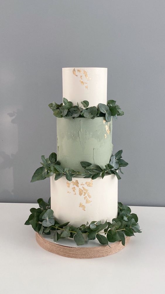 a stylish wedding cake with white and sage green tiers, gold leaf and greenery is amazing for many weddings