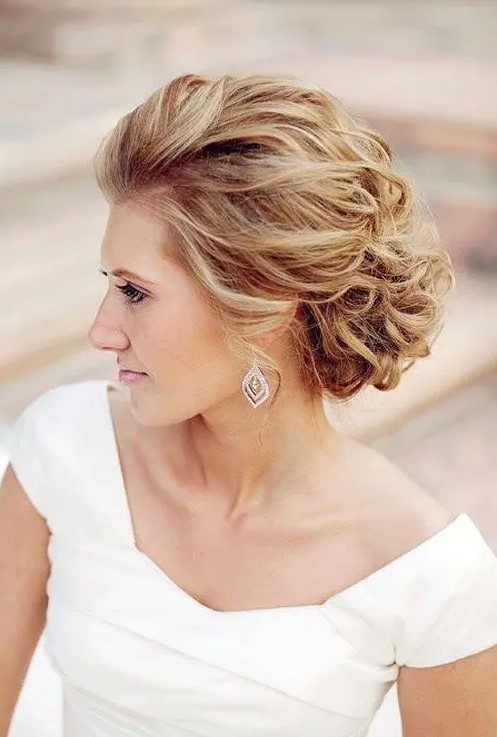 an airy and breezy wavy updo with curls and volume on top for an elegant feel