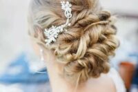 65 a twisted low updo on long hair with a rhinestone hairpiece on one side for a refined look at a beach or some other wedding