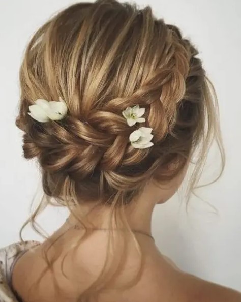 a braided updo with locks down, a dimensional bump and fresh blooms tucked into the braid