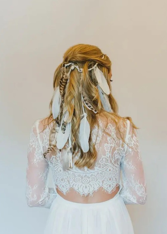 a half updo with a bump and waves spruced up with a lot of feathers is inspired by vikings and is ideal for a boho bride