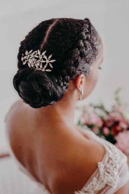 a stylish updo with side braids and a braided low bun plus a large floral hairpiece is a chic and cool  idea for a wedding