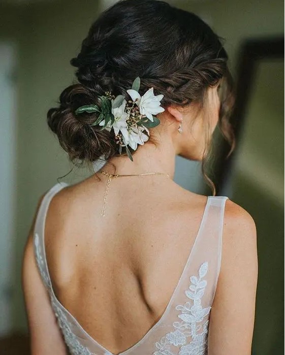 braided and twisted updo with locks down and flowers and greenery tucked in on only one side is a romantic and chic idea