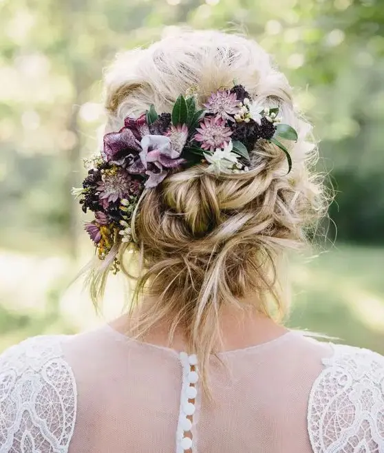 a messy twisted low updo with some hair down and moody fresh blooms plus a bump