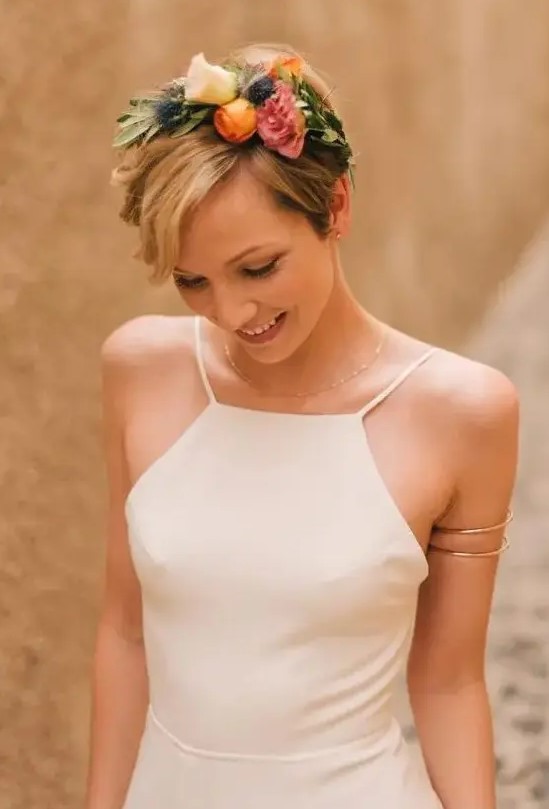 a short haircut accessorized with a colorful fresh flower headband of pink, orange, white flowers, greenery and thistles