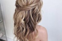 a simple and catchy textured wavy half updo with a twisted halo and a bump on top is a cool and chic idea for a wedding