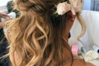 a twisted wedding half updo with a messy wavy bump and waves down plus some fresh blooms is classics