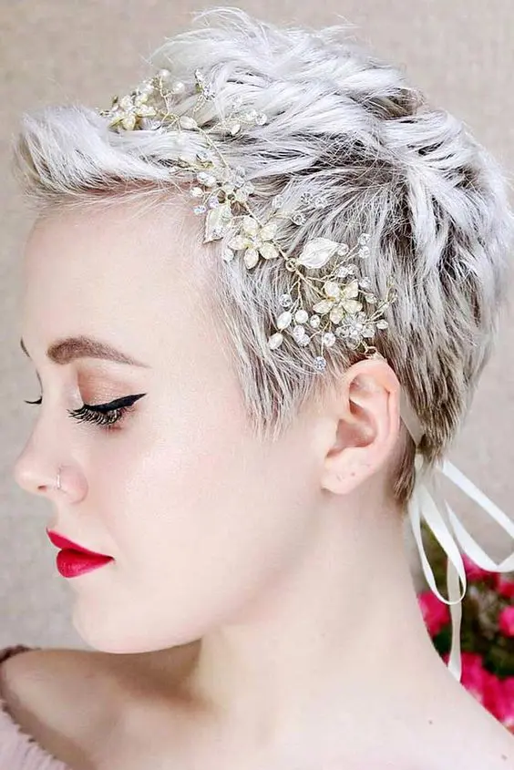 an icy blonde pixie haircut with waves and texture is accented with a rhinestone and pearl headband and looks cool