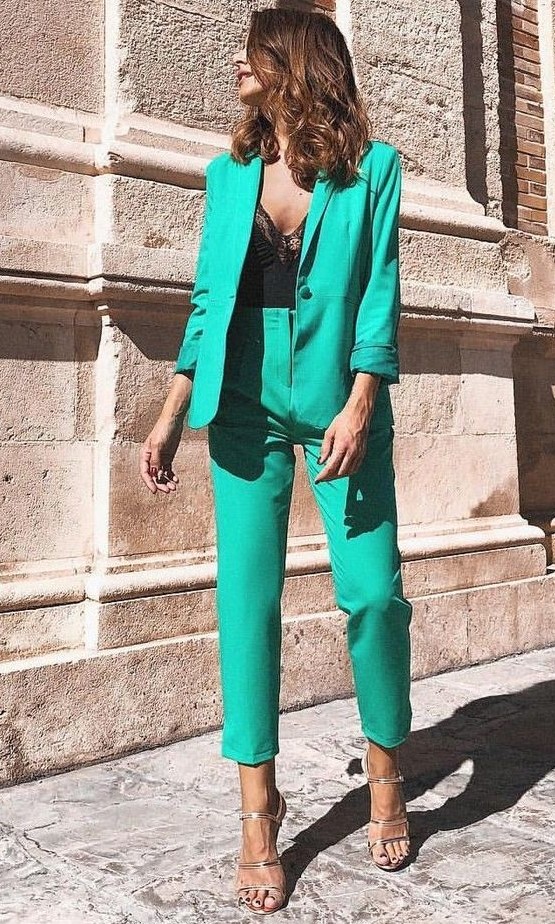 a green pantsuit with an oversized blazer, silver heels and a black lace bodysuit for a refined and chic fall wedding