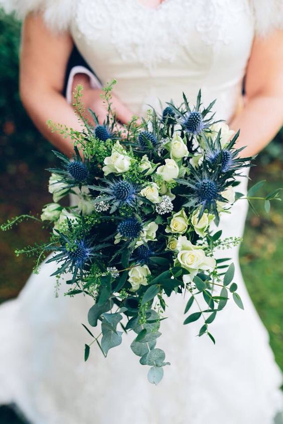 a lovely wedding bouquet of white roses, thistles, greenery and herbs is a cool idea for a summer wedding, it's classics