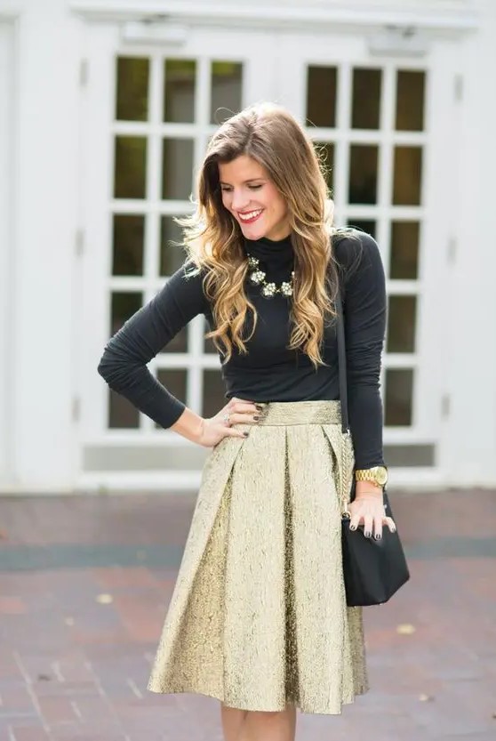 a gold pleated skirt, a black turtleneck, a statement necklace and a black and gold bag for a glam wedding