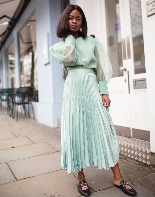 a mint green pleated midi skirt styled with a matching blouse with puff sleeves and floral slip mules