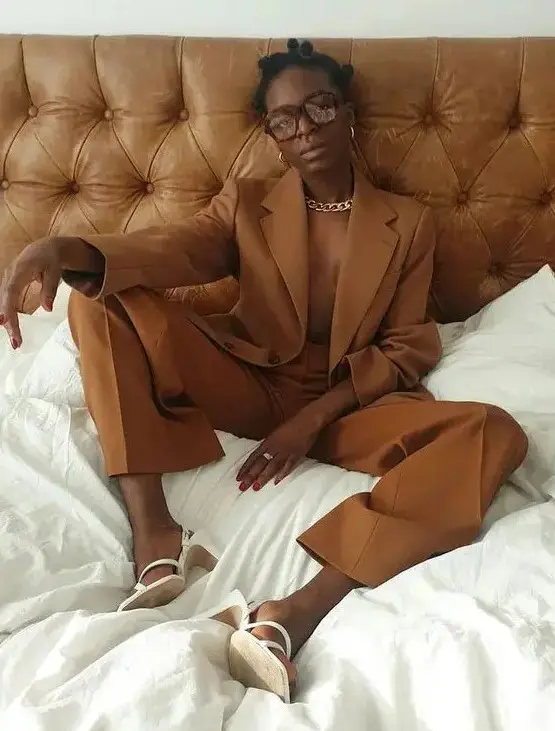 a rust-colored pantsuit, white slingbacks, a statement chain, gold earrings for a bold look