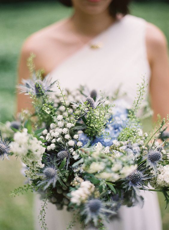 a super textural wedding bouquet of white blooms, blue thistles, greenery and other fillers is a lovely idea for a greenery-filled wedding