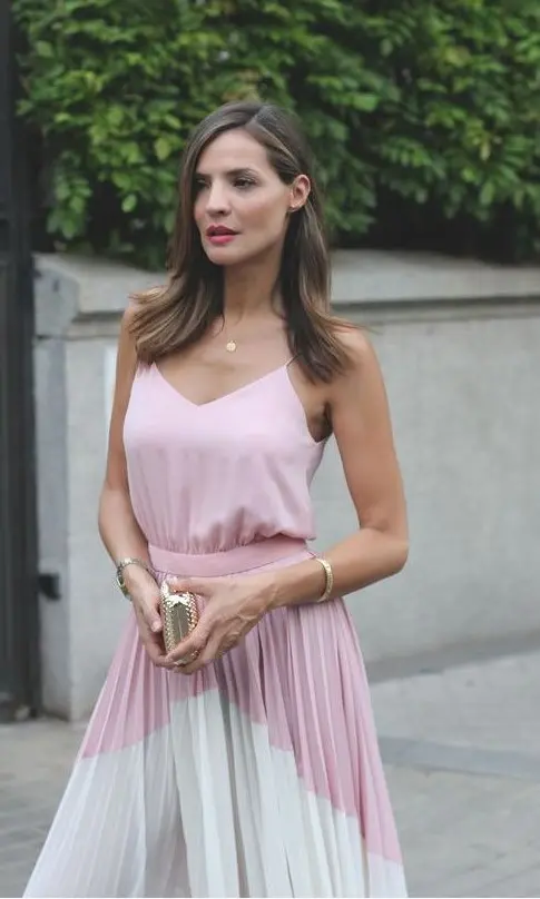 a pink spaghetti strap top, a color block pink and white pleated midi skirt and a tiny metallic clutch