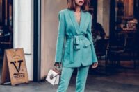 12 a turquoise pantsuit with an oversized blazer with a sash and pants with slits, sheer shoes and a white bag are lovely
