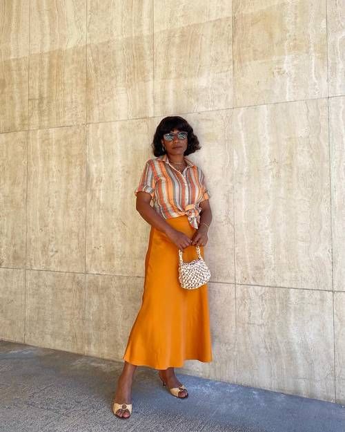 a bold and casual summer wedding guest look with a striped shirt, an orange slip midi skirt, chic shoes and a woven bag