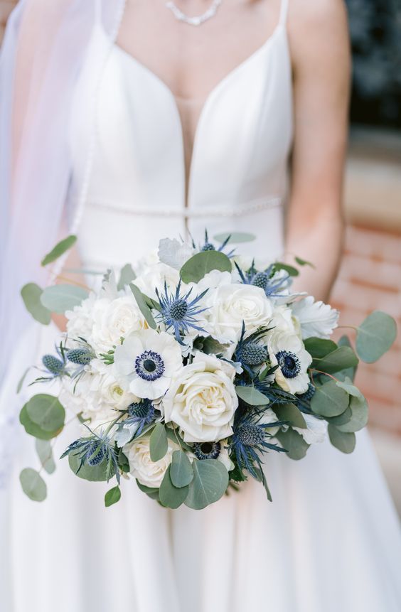 a chic and classic wedding bouquet of white roses and anemones, thistles and greenery