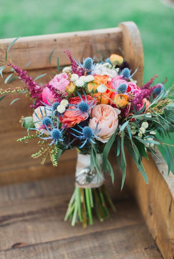 a colorful summer wedding bouquet with hot and blush pink blooms, thistles, berries, amaranthus and greenery