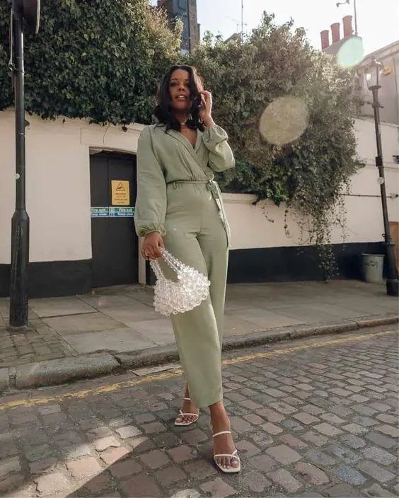 a green jumpsuit, white strappy shoes, a beaded bag for a spring or summer wedding