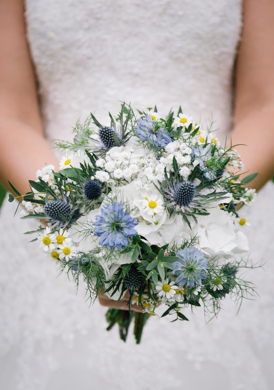 a delicate summer wedding bouquet of white and blue blooms, thistles, greenery and chamomiles is a cute idea for your celebration