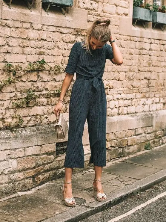 a polka dot jumpsuit with cropped pants, short sleeves, neutral platform shoes and a small matching bag