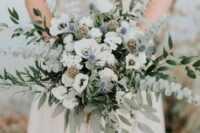 30 a dimensional wedding bouquet of white anemones, blue thistles, roses, greenery and seed pods is a bold and catchy idea, though the color palette is neutral