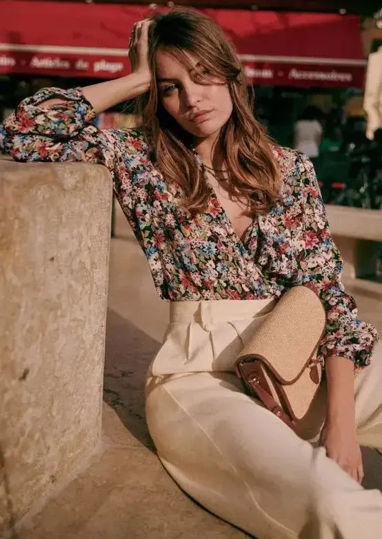 A bold floral wrap blouse with short sleeves, creamy high waisted pants and a small bag are a cool combo for a casual summer wedding