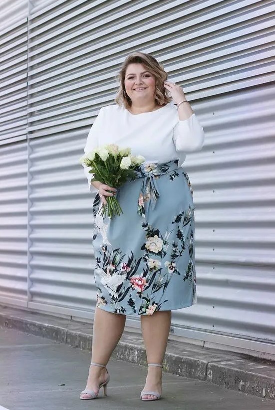 a tender spring wedding guest of a white top with long sleeves and a powder blue floral midi skirt, off-white shoes