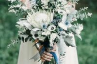 40 a lovely wedding bouquet of a king protea, white anemones and blooming branches, greenery and blue ribbons is chic for spring or summer