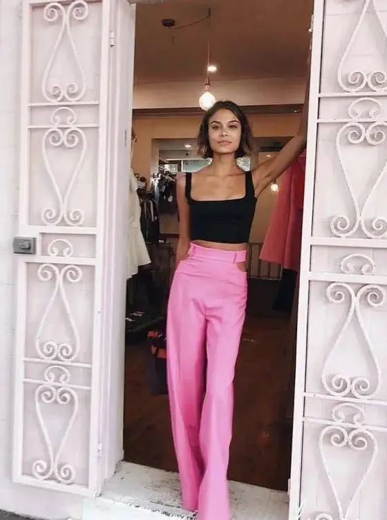 a stylish and catchy wedding guest look with a black crop top and hot pink high waisted trousers with cut out sides is amazing for summer celebrations