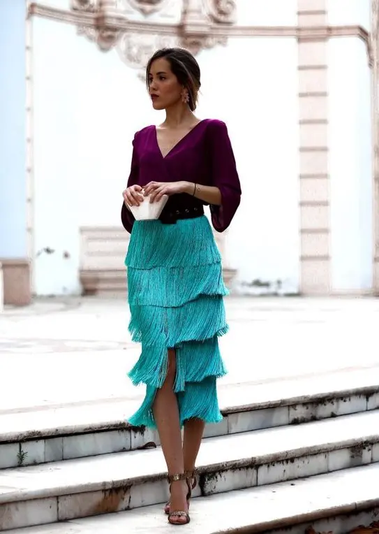 a catchy color block wedding guest outfit with a purple blouse, a turquoise fringe midi, a black belt and metallic shoes