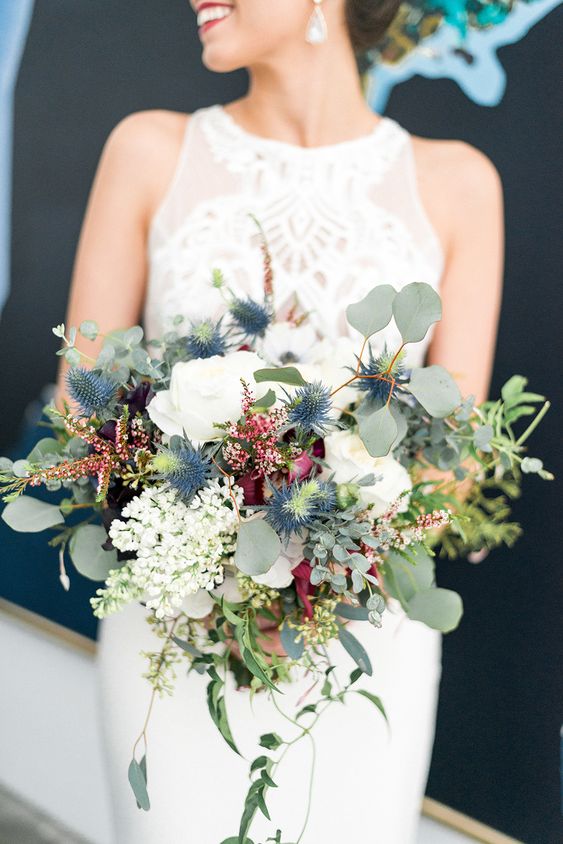 a textural wedding bouquet of white roses, various wildflowers, thistles, greenery and cascading elements is a lovely idea