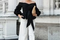 55 white culottes, a black off the shoulder draped top with long sleeves and ties, black heels and a creative bag