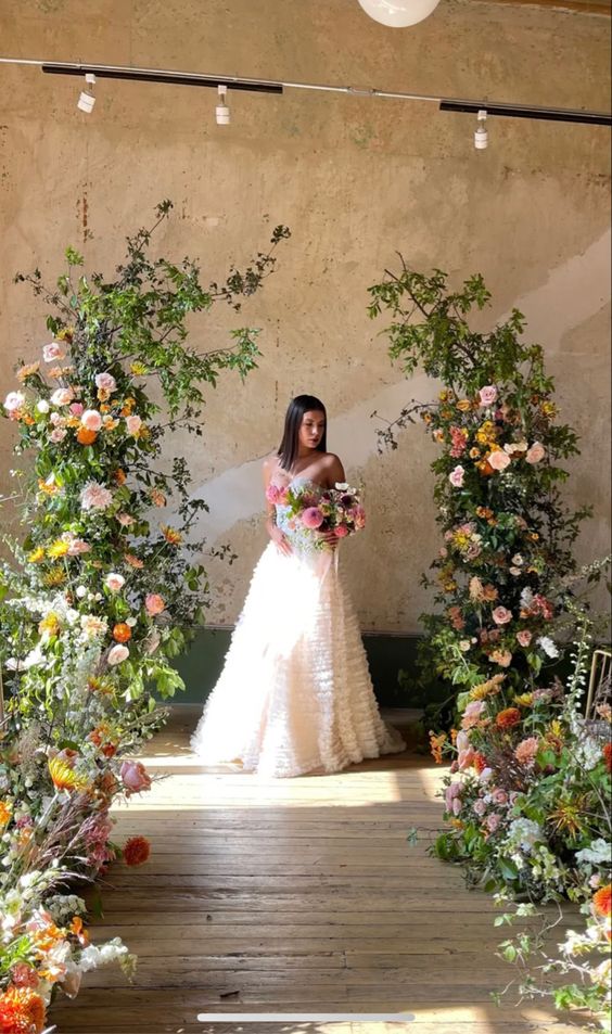 a beauitful spring to summer wedding altar of greenery, lush blush and orange blooms and grasses is amazing to rock