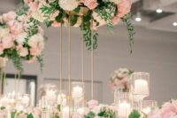a beautiful and refined tall wedding centerpiece of white hydrangeas and pink roses and greenery and matching arrangements on the table