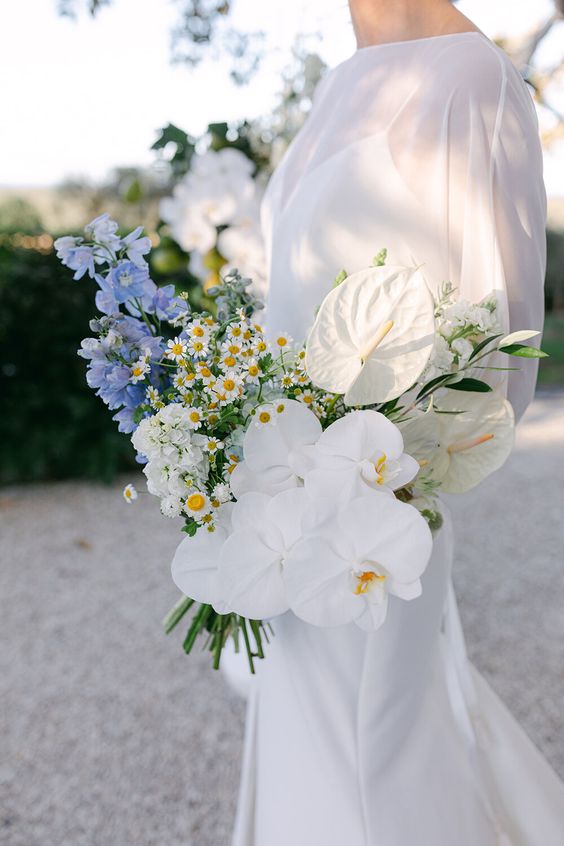 a wedding bouquet of blue blooms chamomiles white orchids and tropical blooms is a gorgeous idea of a mixed wedding bouquet (styling by Aegean Styled Shoot)