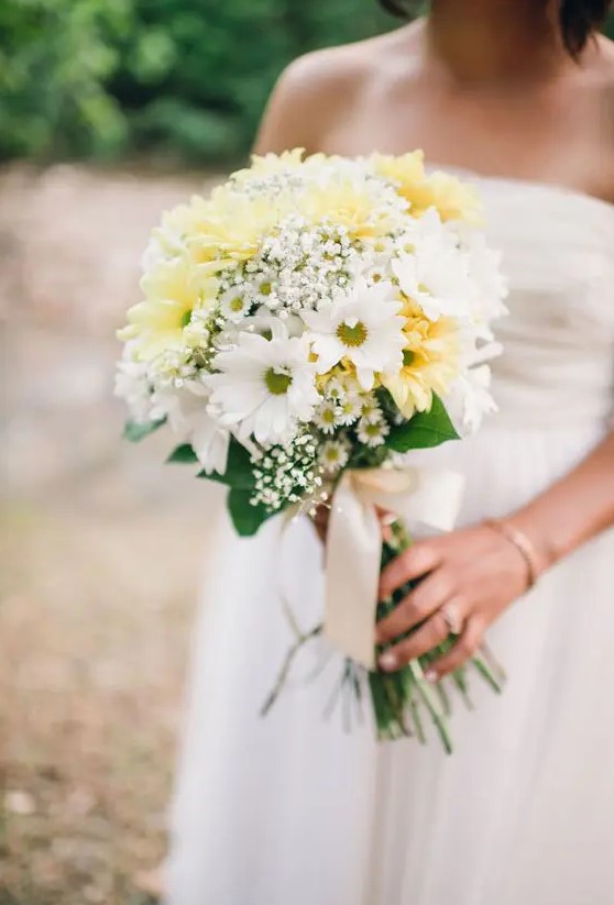 a beautiful wedding bouquet of white and yellow gerberas, baby's breath and greenery plus neutral ribbon for a spring or summer wedding
