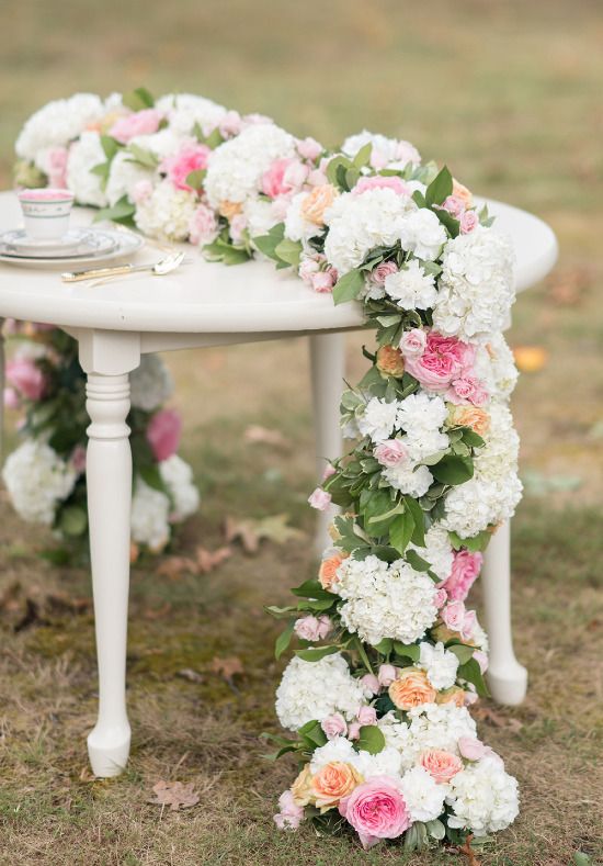 a beautiful wedding table runner with white hydrangeas, peachy and pink peony roses and greenery is a lovely solution